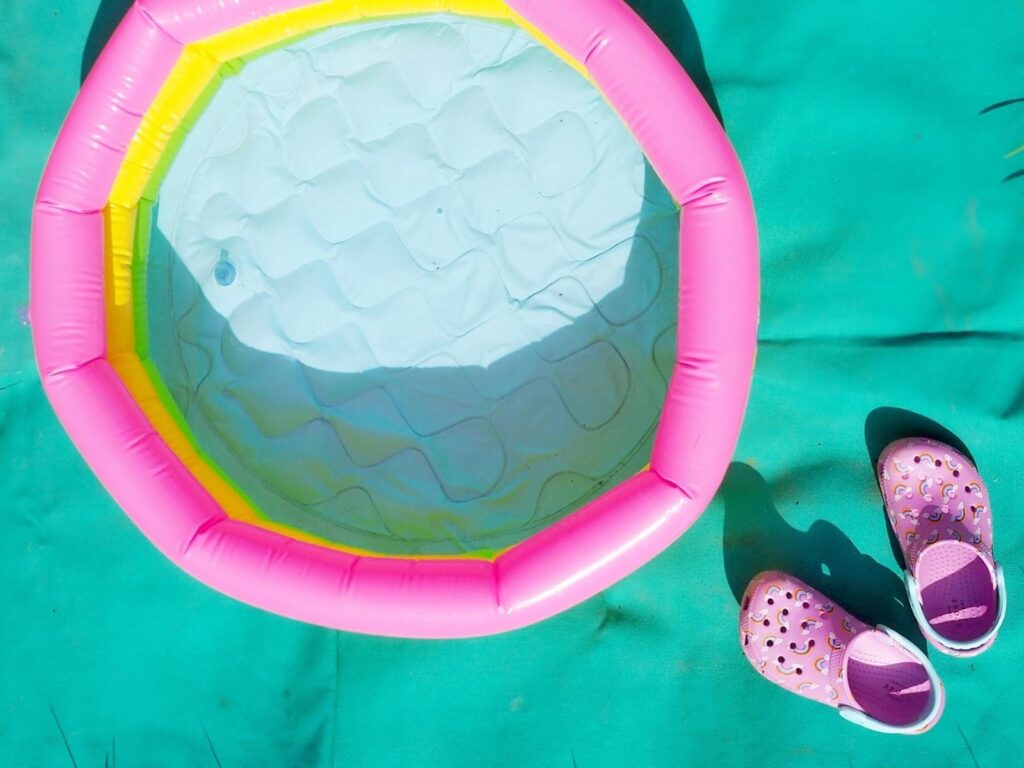 Ružové detské topánky Crocs vedľa malého farebného bazéna