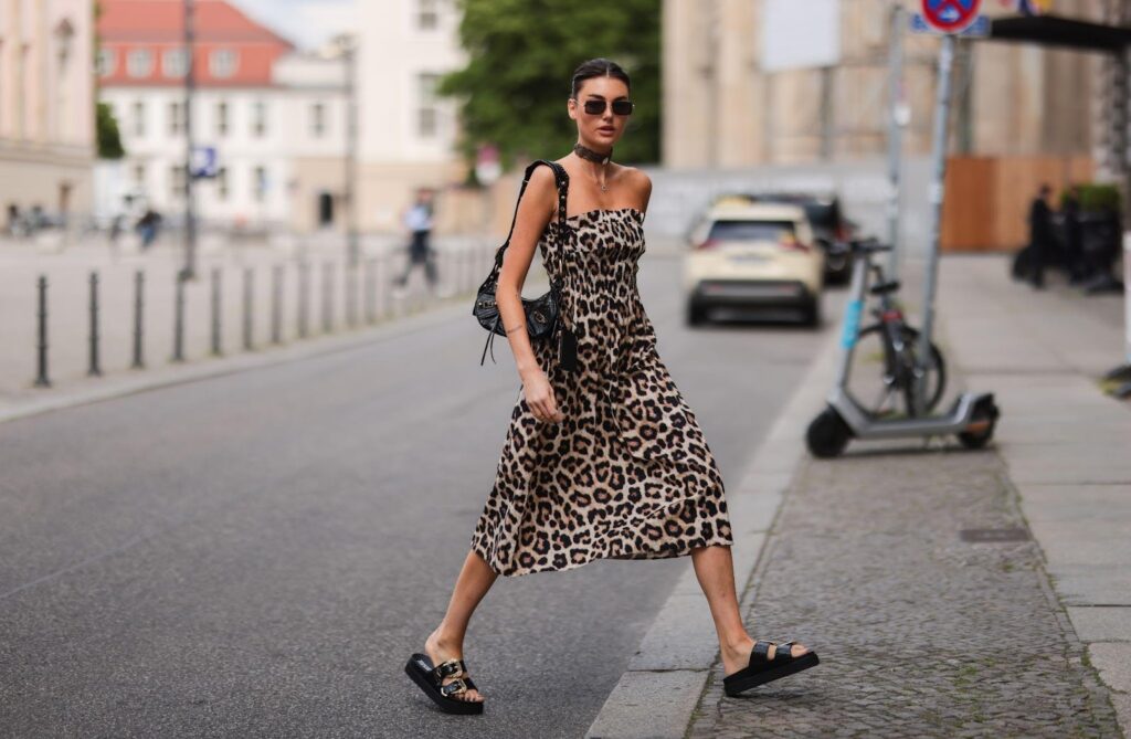 cez ulicu prechádza mladá žena v ľahkých vzdušných šatách s leopardím vzorom