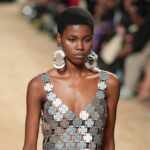 módne doplnky na rok 2024 – žena v masívnych strieborných náušniciach a strieborných šatách zo spojených kovových plátov